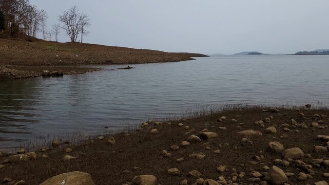 Calm Lake Landscape with Rocky Shoreline and Trees in Natural Environment