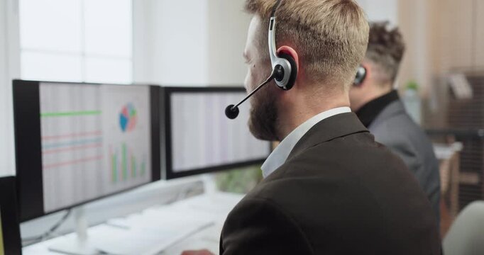 Agent operator with headset on call support. In a modern office a computer shows analytics as teamwork serves customers. Staff optimize response time. Data driven service efficiency concept.