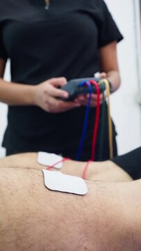 Physical therapist applying electrodes for muscle stimulation therapy