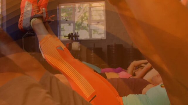 Fitness group following start, performing V-up reps in sync, training core, orange overlaying mats