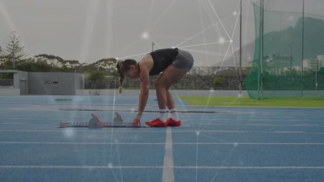 Sprinter adjusting blocks on blue track, preparing for sprint while particle overlay tracing motion