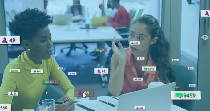 Pink-shirted woman pointing at laptop, yellow peer checking metrics, causing social badges to float
