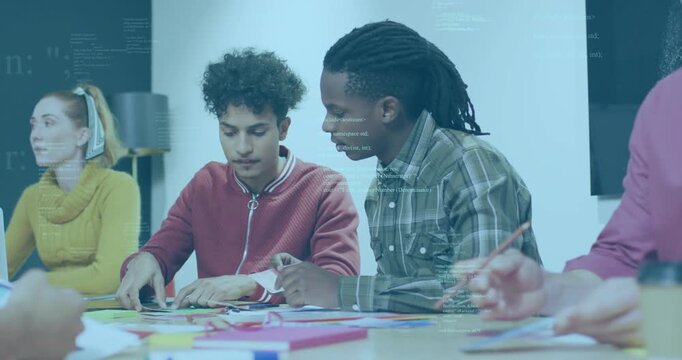 Male peers leaning, folding, aligning paper parts in design lab, code overlays appearing over table