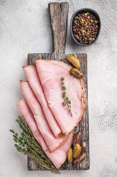 Spalla or lonza arranged neatly on aged wood with herbs and olives placed on a gray stone surface ideal for food stock compositions.