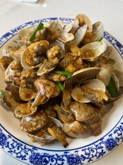 Fototapeta premium Asian Stir-Fried Clams in Garlic Sauce on Blue and White Porcelain Plate