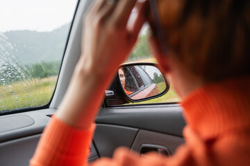 Fototapeta premium Woman relaxing in a car during the rain in the forest. Selective focus. Green forest and mountains in the background.