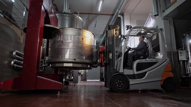 Forklift truck places a chrome-plated basket of grapes into a hydraulic press to produce wine. 