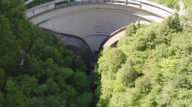 Aerial drone view of the Senaiga dam and the turquoise artificial Lake Senaiga surrounded by lush forest, steep rock walls, and mountain scenery in summer in Lamon, Belluno, Veneto, Italy