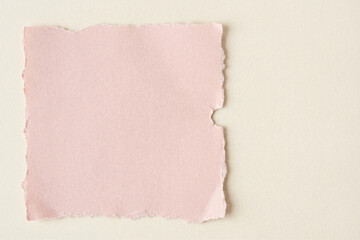 Obraz premium Blank pink torn paper square with deckled edges on a light beige background, perfect for rustic wedding invitations, scrapbooking, or elegant note cards.