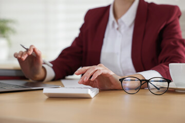 Fototapeta premium Professional accountant using calculator at wooden table in office, closeup