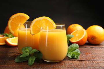 Citrus juice in glasses, fresh oranges and mint leaves on wooden table, closeup © New Africa