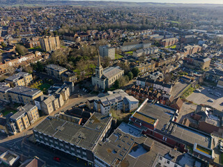 Fototapeta premium Residential area in Maidstone town, Kent, UK. Aerial view of Madstone East with tall church as a landmark. Quiet streets on a sunny Sunday morning. Urban landscape with buildings and trees.