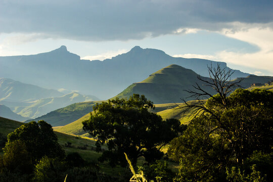 Jagged peaks of the Drakensberg mountains in the late Afternoon, with the iconic bowl-shaped double peak of Giant&rsquo;s Cup, blue in the background