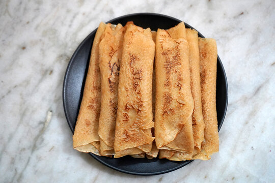Traditional Bengali Sweet Patisapta Pitha Rolled Crepes on Black Plate