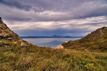 Obraz premium Aerial view of a remote sandy beach and rugged coastline with mountains and island under a moody sky, on the Bukhtarma Reservoir, on the Irtysh River, in Kazakhstan (Qazaqstan)
