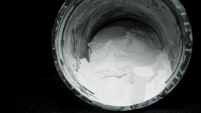 Taking a Measuring Spoon from the Jar with Creatine. a Bag with Silica Gel Inside to Absorb Excess Moisture. Dolly slider, close up.