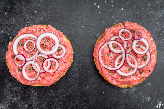 Mettbroetchen German pork sandwiches with raw minced pork spread onion rings and herbs on black plate
