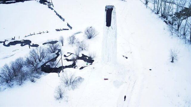 A frozen water tower. The water has turned to ice. It's abnormally cold. An ice-covered iron structure that holds water. An ice-covered iron water tower.