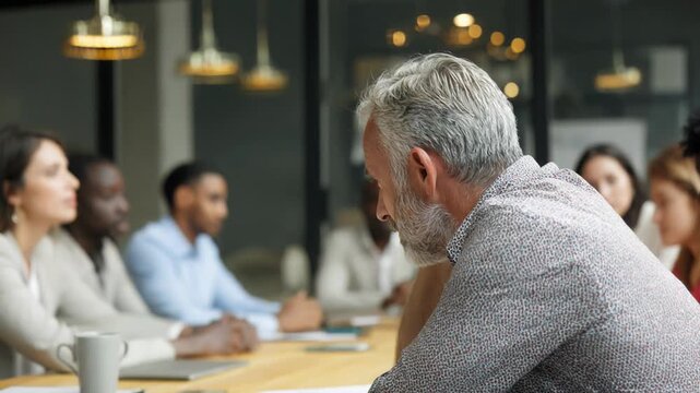 Mature businessman looking tired and bored during a meeting with colleagues in the background
