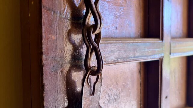 A heavy iron chain hangs against the polished wood of an antique door at Kanak Vrindavan Mahal. This close-up captures the rugged, historic textures found throughout the Jaipur complex.