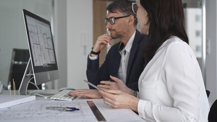 Architects collaborating on building project, discussing blueprints and 3d models in an office...