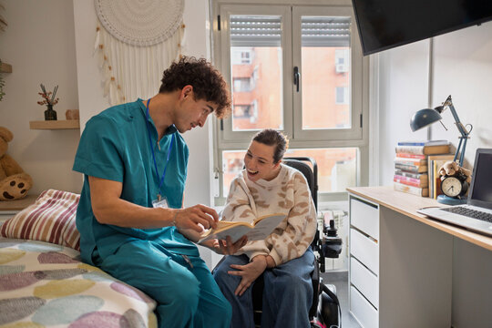 Caregiver reading book to happy disabled woman