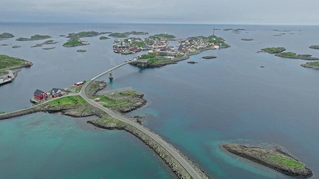 Drone aerial showing Henningsv&aelig;r village connected by bridges across small islands in the Lofoten archipelago. Scenic fishing village surrounded by calm Arctic waters.