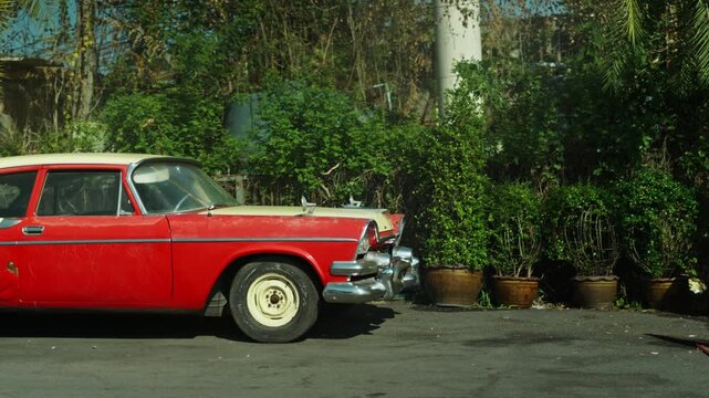 Retro red car standing on asphalt road at sunset
