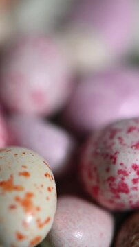 Close up of chocolate-covered peanuts with bright colorful candy coating rotating on a turntable. Shiny surface, detailed texture of chocolate and glaze, and vibrant colors highlighted in high definit