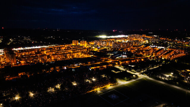 Aerial drone footage of a small provincial town in Poland at night, glowing street lights, quiet urban landscape, peaceful atmosphere, and illuminated roads under dark sky.