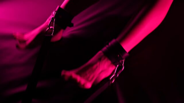 Women's legs in leather shackles. BDSM fetish.