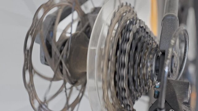 Close up of rear wheel with cassette, chain and disc brake rotor. Shifting gears on bicycles transmission. Cycling equipment and bike drivetrain maintenance