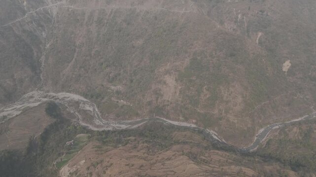 Top-down aerial view of Sainji corn village near Mussoorie, Uttarakhand, with terrace farms and houses forming abstract patterns on misty slopes, with the Aglar River flowing below.