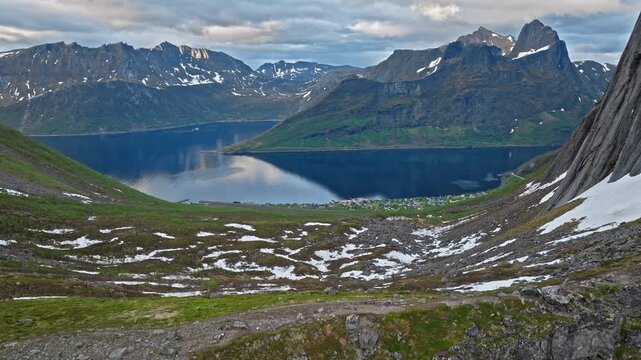 Aerial view from the mountain plateau near Segla on Senja Island, Norway. Fjord waters stretch beneath steep peaks and rugged Arctic terrain.