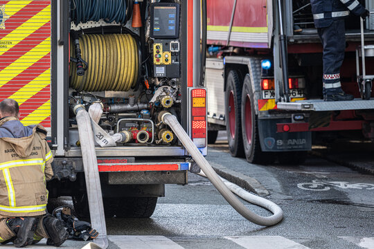 Gothenburg, Sweden - February 25 2023: Firefighter connecting hoses to fire truck during emergency response.