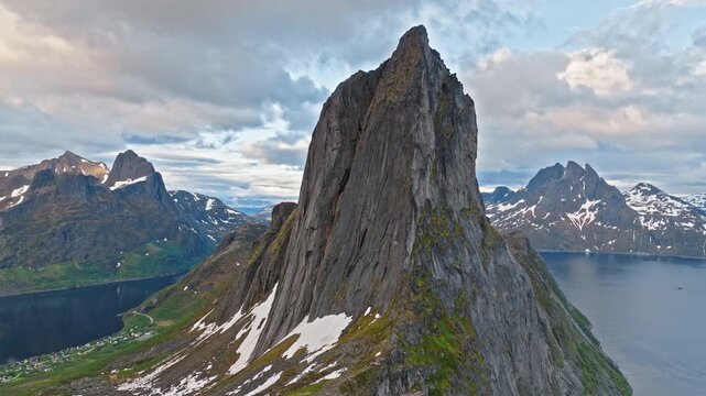 Aerial view of the iconic Segla mountain peak rising sharply above the fjord on Senja Island, Norway. Dramatic Arctic landscape with steep cliffs and distant snow-covered mountains.
