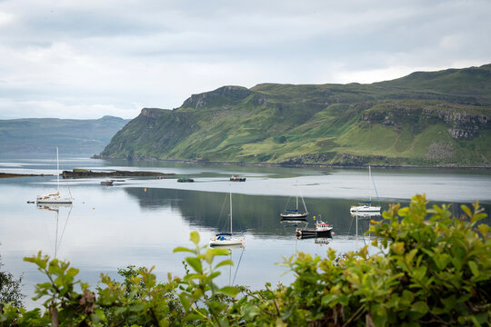 Small boats anchored in a calm bay with mountain landscape on the Isle of Skye, Scotland