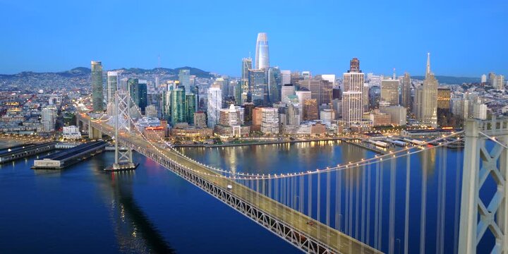 San Francisco - High Aerial Approach Over Bay Bridge Towards SF Skyline at Blue Hour with City Lights & Cars on Bridge