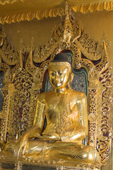 Obraz premium Golden Buddha statue inside ornate Buddhist temple in Yangon, Myanmar