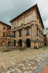 Fototapeta premium A picturesque narrow street in the hilltop town of Montepulciano, Tuscany. Historic Renaissance architecture, flower-filled balconies, and the warm glow of the Italian sun.