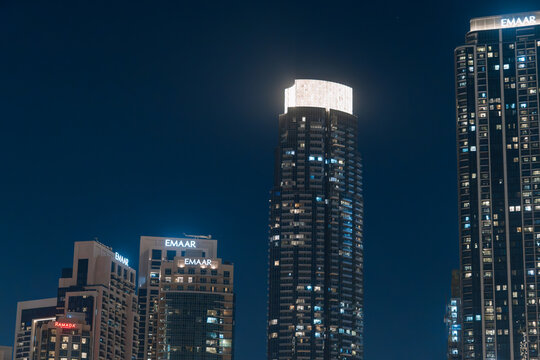 Emaar skyscrapers illuminated at night in Dubai, showcasing modern architecture and urban skyline against a dark sky