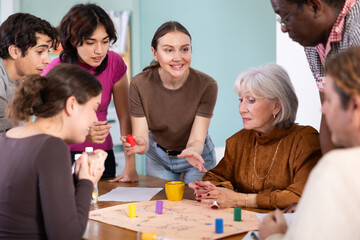 Fototapeta premium Group of different ages playing board game at table in office