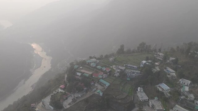Aerial view of Kuee village in Tehri Garhwal, Uttarakhand, near Rishikesh, with the Ganga River flowing through Tota Ghati, surrounded by lower Himalayan hills and forests of sal, peepal, banyan.