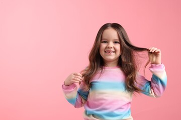 Portrait of little girl on pink background. Space for text