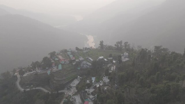 Aerial view of Kuee village in Tehri Garhwal, Uttarakhand, near Rishikesh, with the Ganga River flowing through Tota Ghati, surrounded by lower Himalayan hills and forests of sal, peepal, banyan.