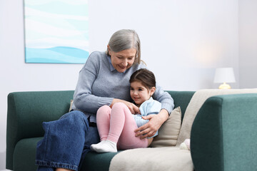 Obraz premium Nanny and cute little girl on sofa at home
