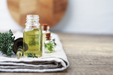 Thyme essential oil, fresh herbs and towel on wooden table, closeup. Space for text © New Africa