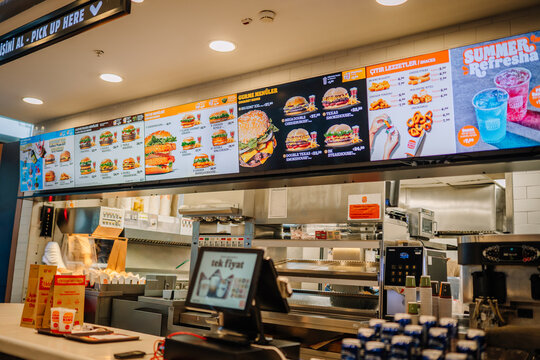 Fast food restaurant interior with digital menu board displaying various meal options and a counter for customer orders