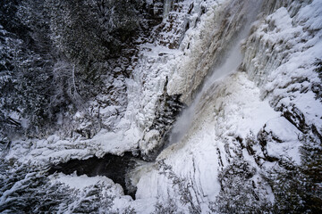 Fototapeta premium View of partially frozen waterfall and river in winter.