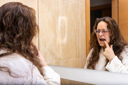 Woman examining teeth in mirror during morning self-care routine